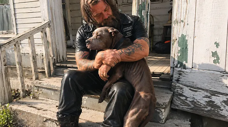 Un motard était assis sur le balcon délabré d&rsquo;une maison abandonnée dans le sud de la ville, serrant contre lui un pitbull affamé